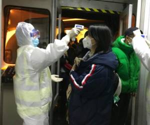 Funcionarios de salud revisan la temperatura corporal de los pasajeros que llegan de la ciudad de Wuhan al aeropuerto de Beijing. Foto: AP.
