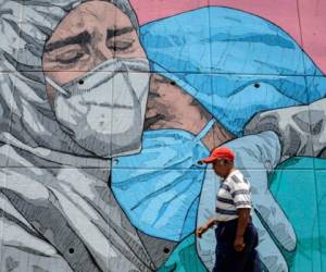Un hombre pasa por delante de un mural relacionado con el coronavirus, en Acapulco. Foto AFP
