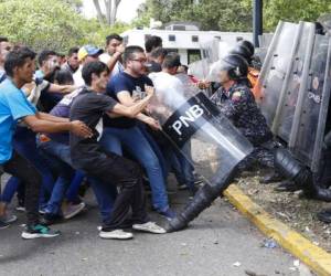 Estudiantes universitarios intentan arrebatarle el escudo protector a un miembro de la Policía Nacional Bolivariana durante enfrentamientos en el exterior de la Universidad Central de Venezuela. Foto: AP.