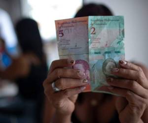 Una mujer muestra nuevos billetes del Bolívar Soberano. Foto AFP