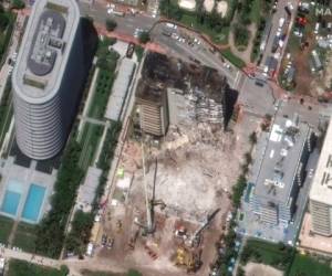 Imagen de satélite facilitada por Maxar Technologies en la que el sábado 3 de julio de 2021 se observan grúas asistiendo en las labores de búsqueda y rescate en la zona donde se desplomó parcialmente el edificio Champlain Towers South, en Surfside, Florida (Maxar Technologies vía AP)