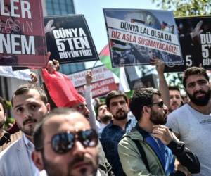 Miembros y partidarios del Partido de la Justicia y los Desarrollos del Partido de Gobierno de Turquía (AKP) sostienen pancartas que dicen que 'el mundo es más grande que cinco' mientras gritan consignas frente al consulado de Israel en Estambul.
