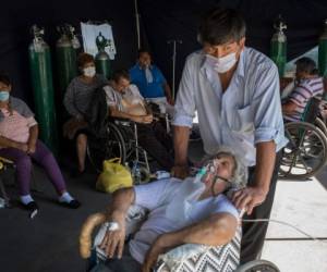Emma Salvador, de 84 años y con una mascarilla de oxígeno para ayudarle a respirar, es vigilada por su hijo José González en una tienda improvisada que se instaló en el Hospital Dos de Mayo para tratar a las personas infectadas con el nuevo coronavirus, en Lima, Perú, el viernes 17 de abril de 2020.