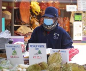 Una mujer usa una mascarilla mientras atiende un puesto de comida en el barrio chino de Londres el viernes 7 de febrero de 2020. (AP Foto/Kirsty Wigglesworth)