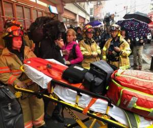 Los bomberos se preparan para llevar una camilla al edificio. Foto: Agencia AP.