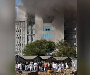 Los trabajadores con equipo de protección caminan después de que estalló un incendio en el Serum Institute de India en Pune el 21 de enero de 2021. Foto: AFP