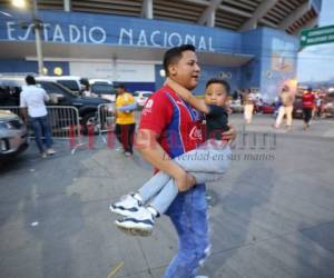 Un padre corre con su hijo en brazos después de los disturbios en el Estadio Nacional. Fotos David Romero| EL HERALDO