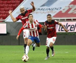 Isaac Brizuela de Guadalajara compite por el balón con Pedro Canelo y José Vázquez de Toluca, durante su partido de fútbol del Torneo de Clausura Mexicana, en el estadio Akron, en Guadalajara, Estado de Jalisco, México, el 16 de enero , 2021, durante la pandemia del coronavirus Covid-19.Ulises Ruiz / AFP.