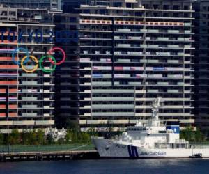 Banderas nacionales colgadas de los balcones en los alojamientos para deportistas, mientras Tokio se prepara para los Juegos Olímpicos, el domingo 18 de julio de 2021. Los JJOO, aplazados por la pandemia, comienzan el 23 de julio sin espectadores en la mayoría de las sedes. (AP Foto/Charlie Riedel)