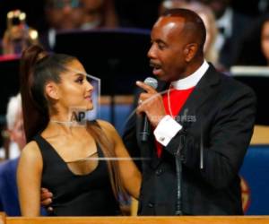 El obispo Charles H. Ellis, III (derecha) toma a la cantante Ariana Grande mientras habla durante el funeral en memoria de Aretha Franklin en el Templo Greater Grace de Detroit, el viernes 31 de agosto de 2018.