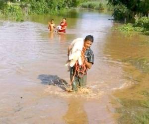 Un campesino, su mujer e hijo caminan en un sector de la Costa de los Amates, anegado por las lluvias y la crecida del río Goascorán. (Foto: Copeco)