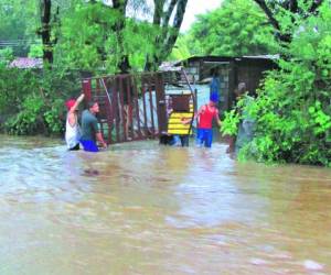 Una familia del barrio Suyapa saca los enseres de su vivienda en medio de la laguna que se formó en las calles de la comunidad tras el desbordamiento de varias quebradas.