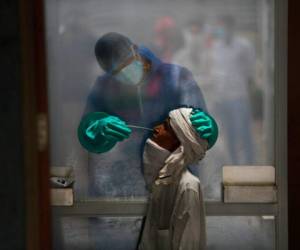 Un trabajador sanitario toma una muestra nasal a una persona para una prueba de detección del coronavirus, en un hospital en Nueva Delhi, India. Foto AP.