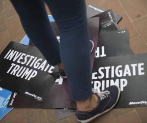 Un manifestante se encuentra en las señales durante una manifestación pidiendo la rendición de cuentas por la presunta complicidad de la campaña Trump con el Gobierno ruso frente a la Casa Blanca en Washington. Foto: AFP