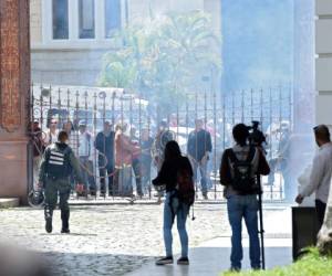 Decenas de personas, algunas encapuchadas, con palos y tubos, y vestidas de rojo, entraron a los jardines del Palacio Legislativo y detonaron cohetes de fuegos artificiales, desatando el caos, constató un equipo de la AFP.