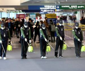 Trabajadores rocían una solución antiséptica en el salón de arribos del Aeropuerto Internacional de Incheon, Corea del Sur, martes 21 de enero de 2020.