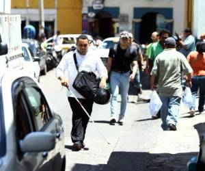 Durante su trayecto por el centro de Tegucigalpa, Dennis Aguilar, un ciudadano de 25 años, tuvo que caminar por la calle porque a su paso se encontraba con agujeros y personas que no le daban espacio. Fotos: Emilio Flores/EL HERALDO.