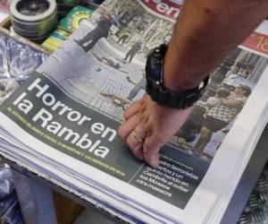 Un hombre toca un periódico que muestra una fotografía de las consecuencias del atentado terrorista en Las Ramblas, en Barcelona, España, el viernes 18 de agosto de 2017.