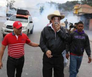 Manuel Zelaya cubre su rostro con una máscara mientras es acompañado por dos de sus simpatizantes en el momento que dirige una protesta en la colonia Miraflores de la capital de Honduras. Fotos: Cortesía.