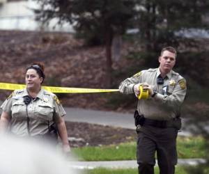 Dos policías acordonan el lugar donde tras tomar rehenes un sujeto hizo varios disparos y mató a tres mujeres. (Foto: AP)