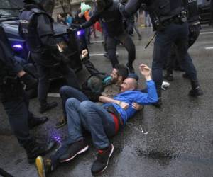 Tres hombres se sostienen el uno al otro mientras tratan de bloquear una furgoneta de la policía española de acercarse a un sitio de votación para evitar que los posibles votantes voten en una escuela asignada a ser una mesa de votación por el gobierno catalán en Barcelona, ​​España. 1, 2017. La policía antidisturbios española ha retirado con fuerza a unos cuantos cientos de aspirantes a votantes de varias mesas de votación de Barcelona. Foto: AP