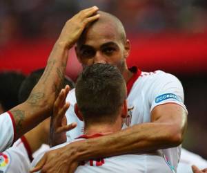 El centrocampista francés del Sevilla Steven N'Zonzi (arriba) es felicitado por sus compañeros tras marcar un gol durante el partido de fútbol de la liga española entre el Sevilla FC y el Club Atlético de Madrid en el Ramón Sánchez Pizjuán. (FOTO: AFP)