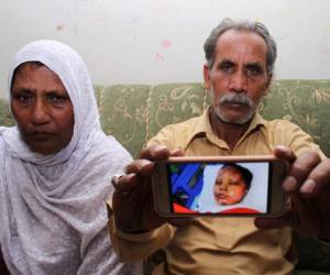Yaqub Masih, muestra una imagen de su hija Asma Yaqub que fue incendiada, con su esposa en Sialkot, Pakistán. Foto: Agencia AFP.