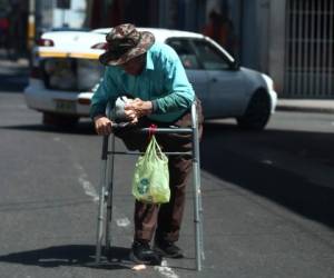 En medio de la calle de la segunda avenida de Comayagüela, un anciano pide limosna.