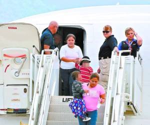 Two women and their children descend for a plane at Palmerola air base in Comayagua, 80 km north of Tegucigalpa on August 11, 2014 after being deported from the US where they had entered illegally. Tens of thousands of migrants - adults and minors - are making the treacherous journey from impoverished Central America to the United States in search of a better life. At least 57,000 children have made the journey since October, triggering a migration crisis that has sent US border and immigration authorities into a frenzy. AFP PHOTO/Orlando SIERRA