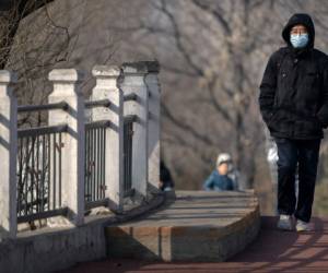 Un hombre, con mascarilla por la pandemia del coronavirus, pasea por un parque público en Beijing, el 2 de enero de 2021. (AP Foto/Mark Schiefelbein)