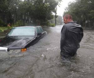 Nick Lomasney caminó sobre fuertes vientos e inundadas calles del Huracán Matthew. /Foto AFP/