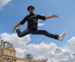 El artista urbano salta en el patio del Museo de Louvre, frente a la pirámide que ocultó con su obra.