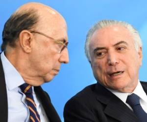 Brazilian Finance Minister Henrique Meireilles (L) and Brazilian President Michel Temer chat during the signing ceremony of a decree that fees differential prices for payment in cash and with credit card at the Planalto Palace in Brasilia, on June 26, 2017. Temer faces his own crisis with the prosecutor general expected to request formal corruption charges against the president Monday or Tuesday. / AFP PHOTO / EVARISTO SA