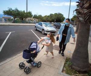 Naidelin, 5, pushes her doll's carriage as she goes out for a walk with her mother Tabata, in Santa Cruz on the Canary Island of Tenerife, on April 26, 2020 during a national lockdown to prevent the spread of the COVID-19 disease. - After six weeks stuck at home, Spain's children were being allowed out today to run, play or go for a walk as the government eased one of the world's toughest coronavirus lockdowns. Spain is one of the hardest hit countries, with a death toll running a more than 23,000 to put it behind only the United States and Italy despite stringent restrictions imposed from March 14, including keeping all children indoors. Today, with their scooters, tricycles or in prams, the children accompanied by their parents came out onto largely deserted streets. (Photo by DESIREE MARTIN / AFP)