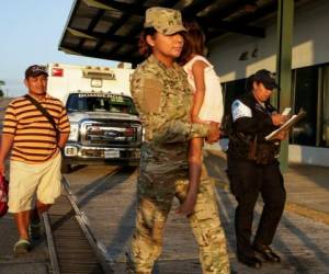 Jose González, izquierda, sigue a su hija de cinco años, cargada por una oficial de policía, tras dejar un hospital en Santiago, Panamá, el jueves 16 de enero de 2020. La esposa de González y cinco de sus hijos están entre las siete personas que habrían sido asesinadas por una secta. (AP Foto/Arnulfo Franco)