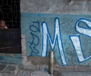 Un niño mira desde detrás de la puerta de su casa, cubierto con graffiti de pandillas Mara Salvatrucha, en Soyapango, El Salvador. Procuradores generales en Centroamérica expresan preocupación.