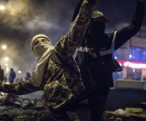 Un hombre con máscara y capucha arroja piedras a la policía durante protestas provocadas por la muerte de un hombre muerto al ser detenido por violar el distanciamiento social en Bogotá, Colombia, jueves 10 de septiembre de 2020. Foto: AP