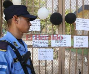 Un oficial observa los mensajes que los estudiantes han colocado en el portón principal del colegio.