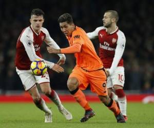 El centrocampista brasileño del Liverpool Roberto Firmino (C) compite con el mediocampista suizo del Arsenal Granit Xhaka (L) durante el partido de fútbol de la Premier League inglesa entre el Arsenal y el Liverpool en el Emirates Stadium de Londres. Agencia AFP.