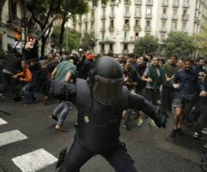 La policía antidisturbios española hace pivotar a un club contra posibles votantes cerca de una escuela asignada a una mesa de votación por el gobierno catalán en Barcelona, España, el domingo 1 de octubre de 2017. La policía antidisturbios española ha retirado con fuerza a unos cuantos cientos de aspirantes a votantes de varias mesas de votación de Barcelona. (Foto AP / Manu Fernández)