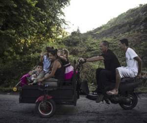 Honduran migrants heading in a caravan to the US, travel on a makeshift motorbike cart in Huixtla on his way to Mapastepec Chiapas state, Mexico, on October 24, 2018. - Thousands of mainly Honduran migrants heading to the United States, a caravan President Donald Trump has called an 'assault on our country', continued their march to the US after one-day rest in Huixtla, Chiapas state in Mexico. (Photo by PEDRO PARDO / AFP)
