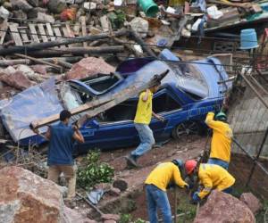 Un grupo de hombres trabaja para despejar escombros después de un deslizamiento de tierra causado por la depresión tropical. Las fuertes lluvias de Selma afectaron la colonia Villanueva, al oeste de la capital de Honduras el 29 de octubre de 2017. / AFP PHOTO / ORLANDO SIERRA