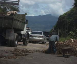 Varias personas se han apostado en la salida que conduce al departamento de Olancho para remendar las calles que se encuentran deterioradas y que no han sido atendidas por la comuna. Foto: Efraín Salgado/EL HERALDO.