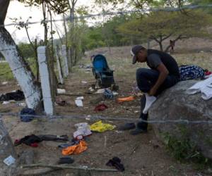 Un migrante se pone los calcetines que dejó atrás cuando su grupo huyó de agentes mexicanos de inmigración corriendo de la autopista a la maleza en Pijijiapan, en el estado de Chiapas, México, el lunes 22 de abril de 2019. (AP Foto/Moisés Castillo)
