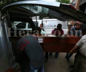Los familiares de Jonathan Josué Espinoza Bustamante suben el féretro con el cadáver de su pariente a una carroza fúnebre. Foto: Estalin Irías/EL HERALDO.