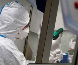 French lab scientist in hazmat gear inserting liquid in test tube manipulates potentially infected patient samples at Pasteur Institute in Paris, Thursday, Feb. 6, 2020. Scientists at the Pasteur Institute developed and shared a quick test for the new virus that is spreading worldwide, and are using genetic information about the coronavirus to develop a potential vaccine and treatments. (AP Photo/Francois Mori)