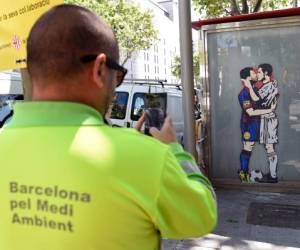 Un trabajador del servicio de limpieza de Barcelona toma una foto del arte callejero 'El amor es ciego' por el artista callejero Salva 'Tvboy' (Foto: Agencia AFP)