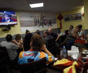 People listen to Catalan president Carles Puigdemont's speech broadcasted on a television screen in a bar in Barcelona on October 10, 2017.Catalonia's leader Carles Puigdemont said he accepted the 'mandate of the people' for the region to become 'an independent republic,' but proposed suspending its immediate implementation to allow for dialogue. / AFP PHOTO / JORGE GUERRERO