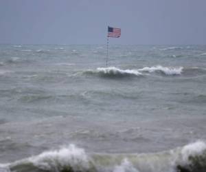 Una bandera estadounidense ondea encima del naufragio del Breconshire el domingo 2 de agosto de 2020 en un mar agitado por la tormenta tropical Isaías, en Vero Beach, Florida. El Breconshire encalló en 1894. (AP Foto/Wilfredo Lee)