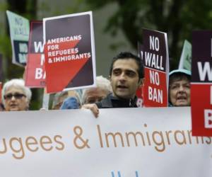 FILE--In this May 15, 2017, file photo, protesters hold signs during a demonstration against President Donald Trump's revised travel ban, Monday, May 15, 2017, outside a federal courthouse in Seattle. A three-judge panel of the 9th U.S. Circuit Court of Appeals on Monday upheld a decision to block the revised travel ban, which would suspend the nation's refugee program and temporarily bar new visas for citizens of Iran, Libya, Somalia, Sudan, Syria and Yemen. (AP Photo/Ted S. Warren, file)